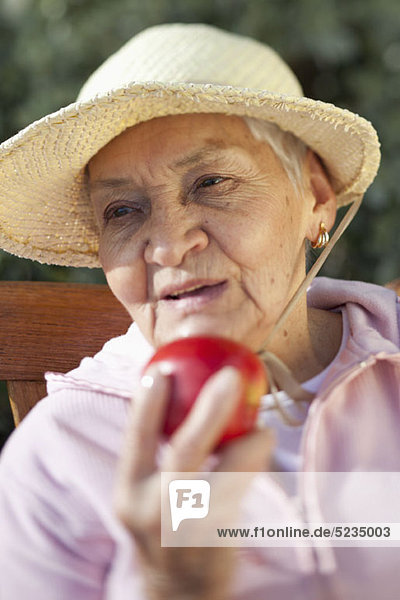 Nahaufnahme einer älteren Frau mit einem Apfel