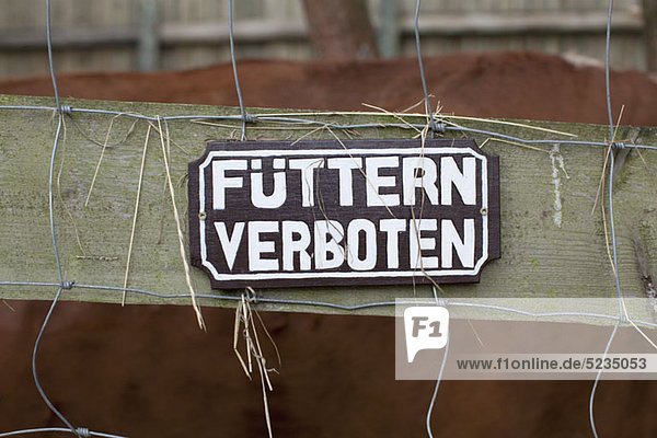 A FEEDING FORBIDDEN Schild in deutscher Sprache am Zaun hängend  Nahaufnahme
