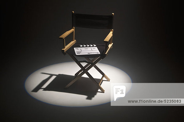 A spot lit directors chair and a clapper board