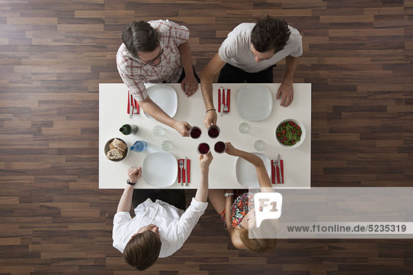 Vier Freunde stoßen bei einer Dinnerparty an  Blick über den Tellerrand