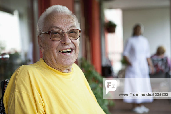 Ein fröhlicher älterer Mann entspannt sich in einem Pflegeheim