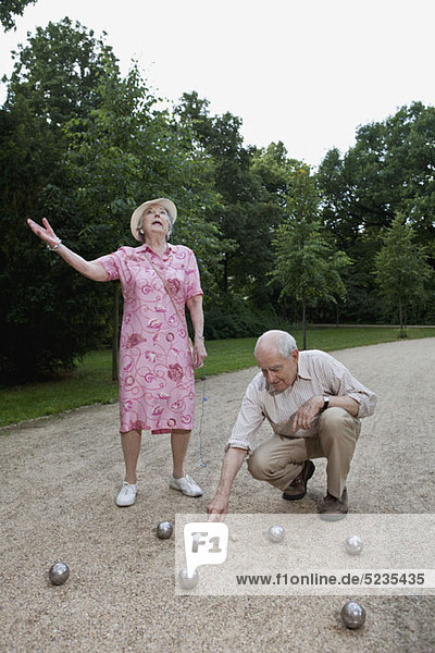 Ältere Männer und Frauen haben Streit beim Boulespielen im Park.