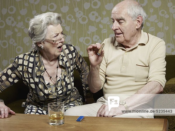 Senior Frau sieht schockiert aus  als der Senior Mann Zigarre raucht.