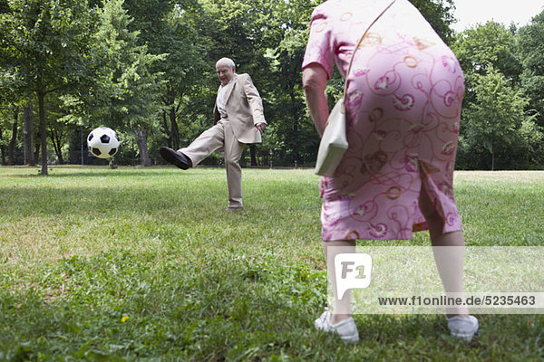 Seniorenpaar spielt Fußball im Park
