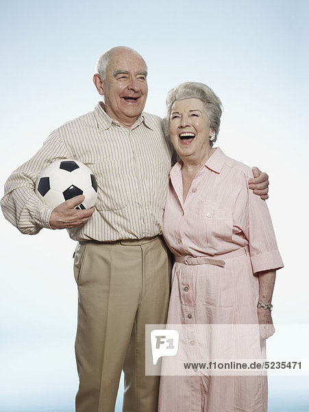 Senior Paar lacht als Mann hält Fußball