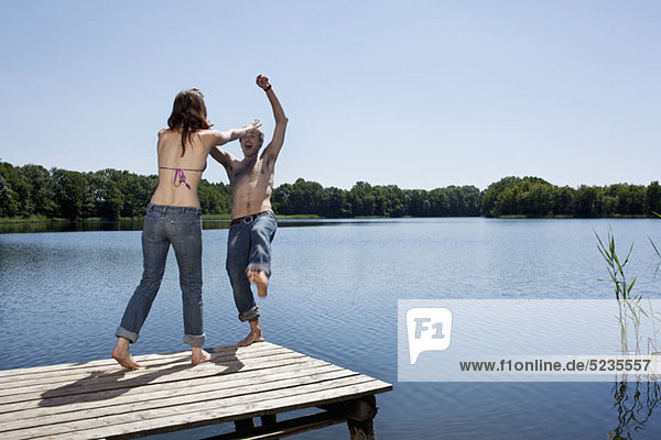 Girl on jetty pushes guy into water