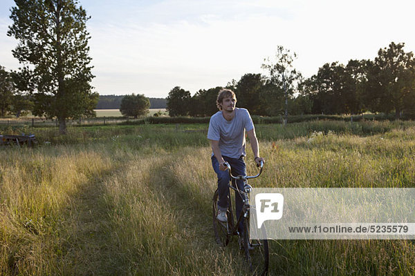 Guy fährt mit dem Fahrrad durch ein abgelegenes Feld.