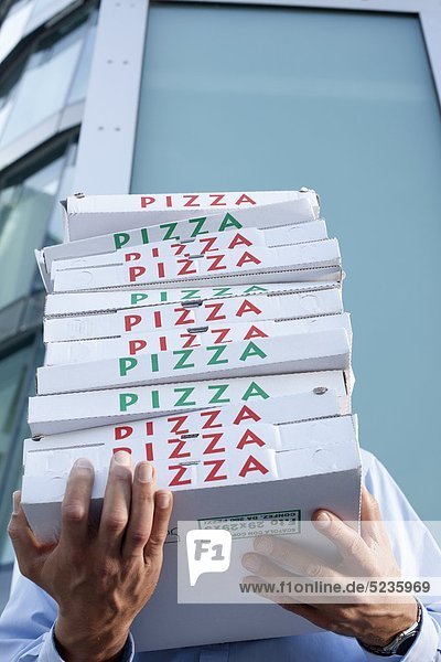 Mann mit Pizzakartons vor seinem Gesicht
