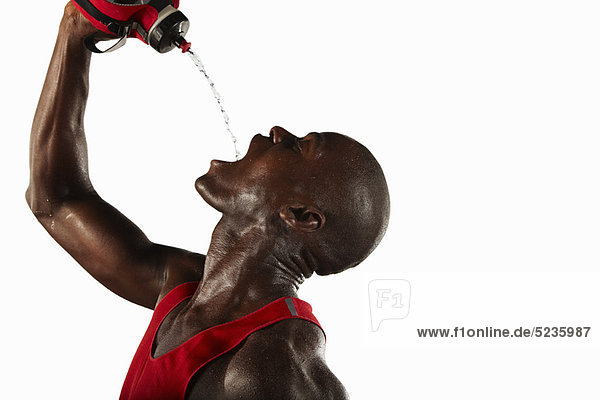 Sportler schüttet Wasser in den Mund.
