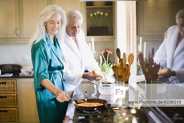 Older couple in bathrobes cooking