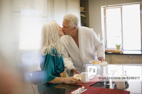 Älteres Paar im Bademantel beim Frühstück