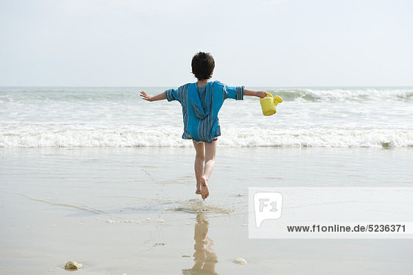 Junge läuft am Strand  Rückansicht