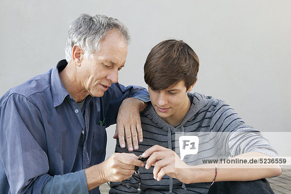 Father and son examining tool together