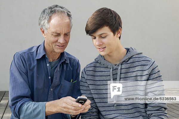 Vater und Sohn benutzen gemeinsam das Handy