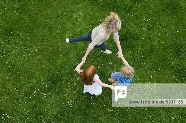 Mutter und Kinder spielen im Gras