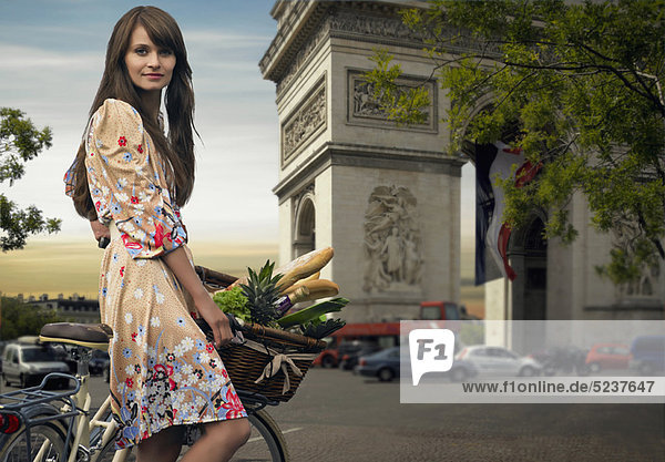 Woman riding bicycle by Arc de Triomphe