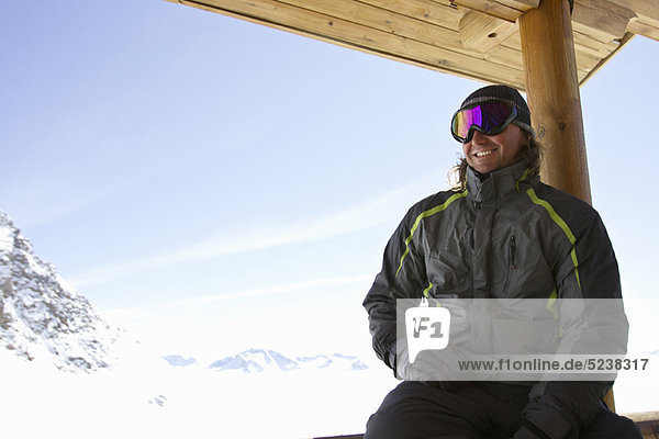 Man relaxing on ski lodge balcony