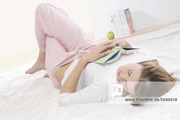 Frau liegt mit Buch im Bett