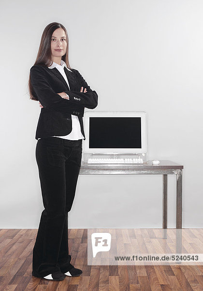 Büro  Frau steht neben Tisch mit Computer