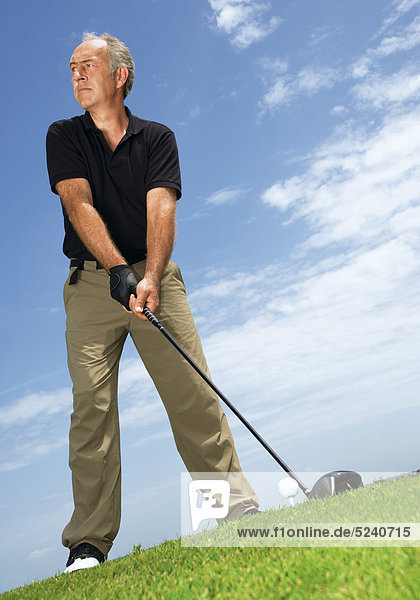 Älterer Mann auf Golfplatz beim Abschlag