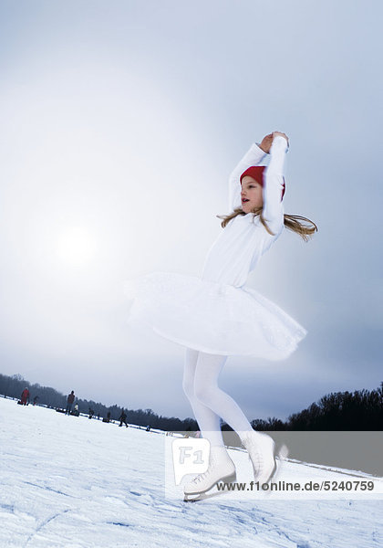 Kleines Mädchen beim Eislaufen auf zugefrorenem See