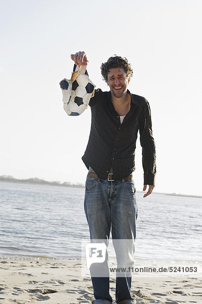 Mann mit zerrissenem Fussball an der Elbe