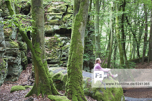 Eifel  Naturpark Südeifel  Blick auf Wanderin auf Buntsandsteinformationen im Buchenwald