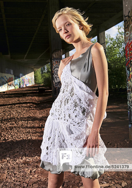 Frau in modischem Sommerkleid vor alter Lagerhalle