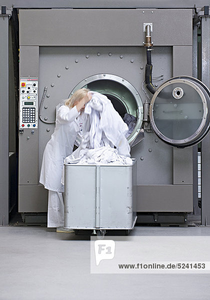 Wäscherei  Frau füllt große Waschmaschine