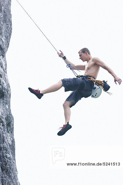 Kletterer hängt in Felswand am Seil