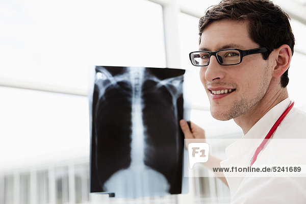 Germany  Bavaria  Diessen am Ammersee  Young doctor examining x-ray  smiling  close up