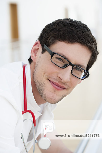 Germany Bavaria Diessen am Ammersee Close up of young doctor leaning on railng with sethoscope smiling portrait