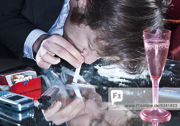 Mann beim Schnupfen von Kokain von Glastisch