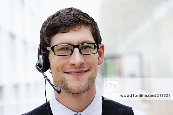 Germany  Bavaria  Diessen am Ammersee  Close up of businesssman with headset  smiling  portrait