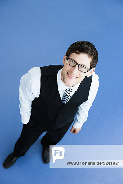 Businessman standing on blue background  smiling  portrait