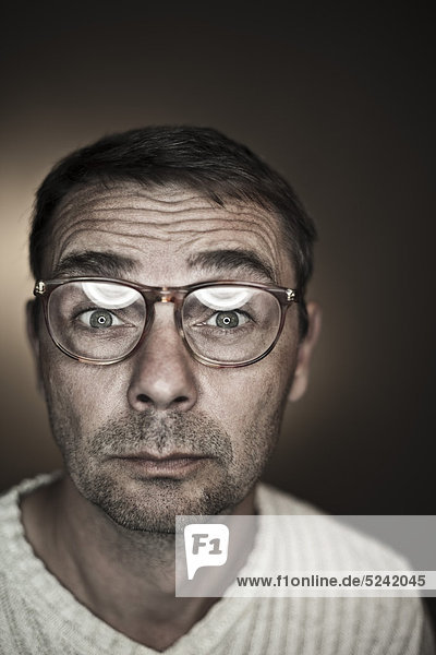 Close up of mature man making funny faces against black background  portrait