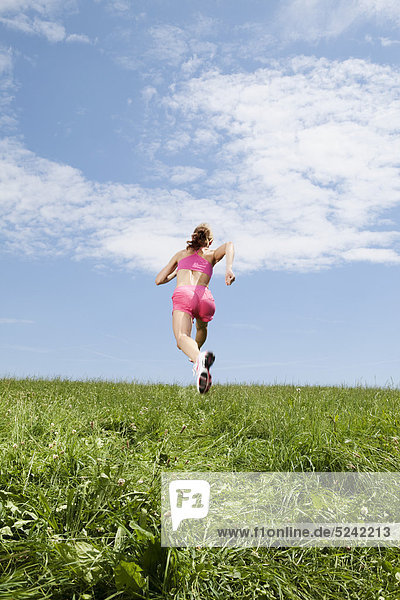 Young woman running on grass