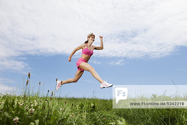 Young woman running on grass