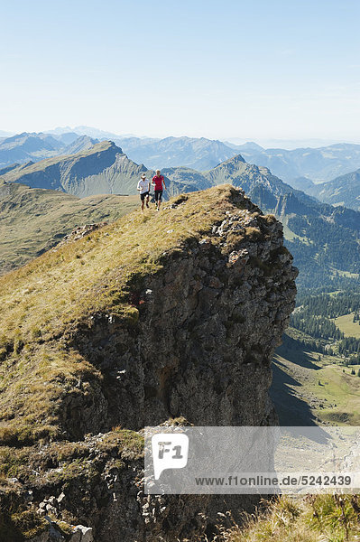 Austria  Kleinwalsertal  Man and woman trail running on mountain cliff