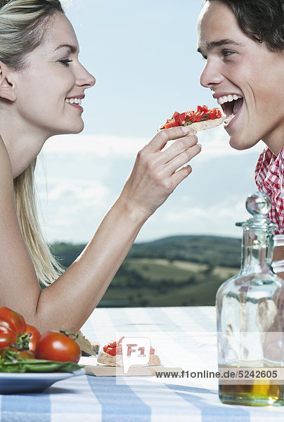 Italien  Toskana  Junge Frau füttert Mann mit Snacks