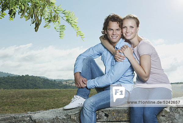 Italien  Toskana  Junges Paar auf Steinmauer sitzend