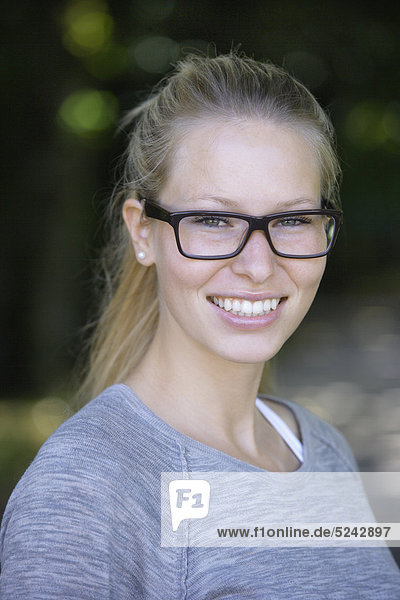 Young woman wearing thick rimmed spectacles  smiling  portrait  close up