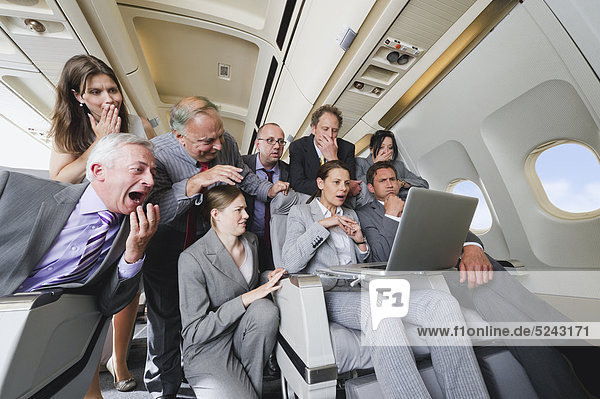 Deutschland  Bayern  München  Gruppe von Passagieren  die im Laptop in der Business-Class-Flugzeugkabine suchen