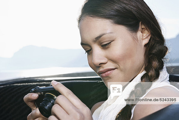 Spain  Majorca  Young woman with camera in car back seat  close up