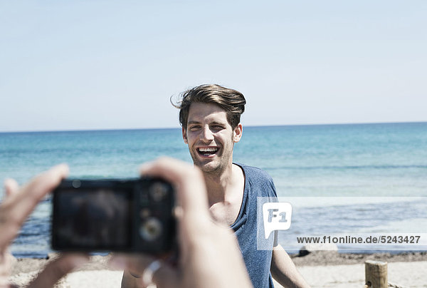 Spanien  Mallorca  Junge Frau fotografiert Mann am Strand