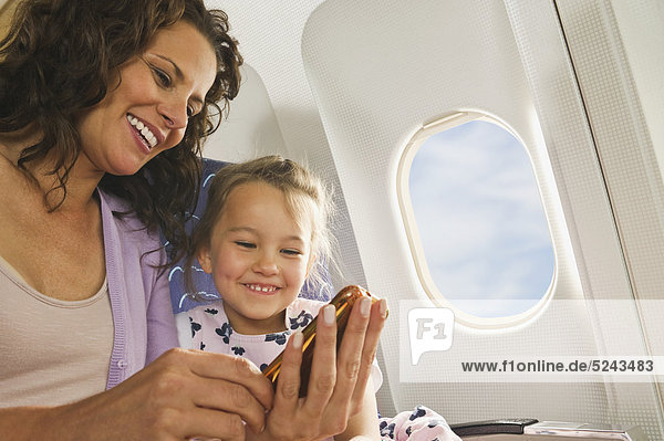 Woman and girl with cell phone in economy class airliner