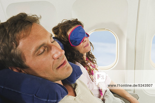 Deutschland  München  Bayern  Mittleres erwachsenes Paar mit Schlafmaske und Übernachtung im Economy Class Airliner