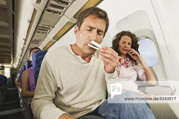 Mann riecht Zigaretten und Frauen ärgern sich im Economy Class Flugzeug