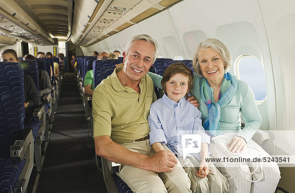 Boy sitting besides senior people in economy class airliner