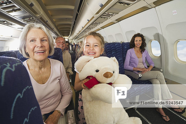 Girl holding teddy bear in economy class airliner